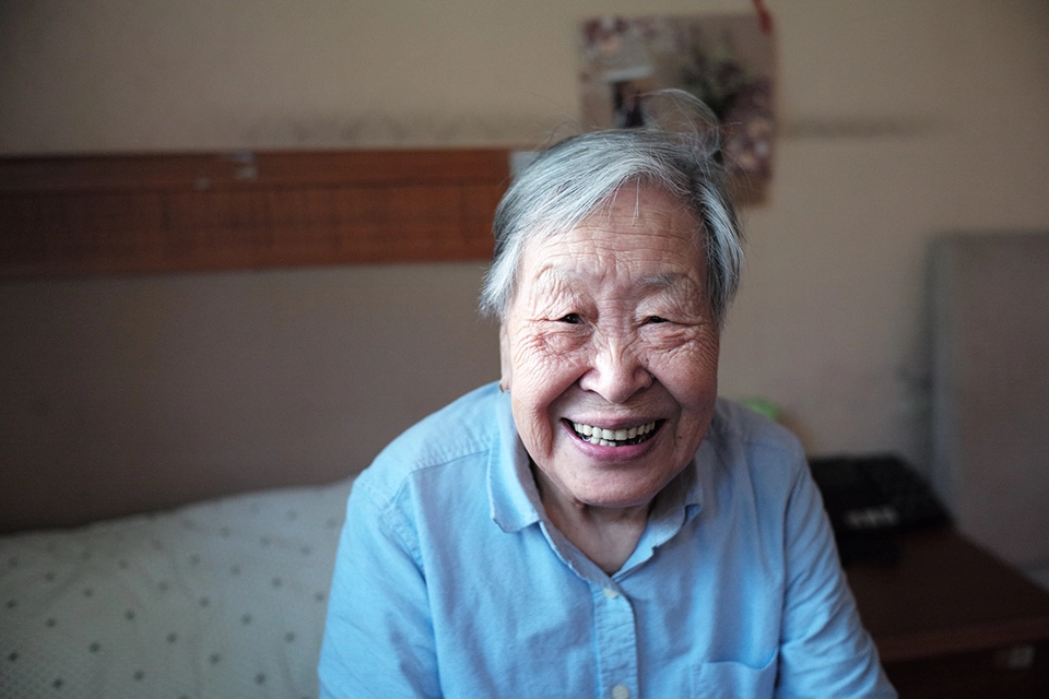 elderly woman sitting on bed smiling